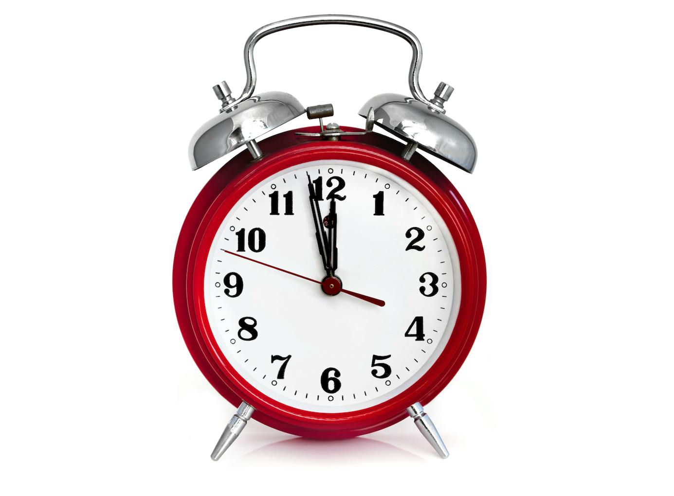 Old red alarm clock, showing two minutes to midnight. Isolated on white.