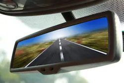 A closeup of a rearview mirror on a car driving fast on a road. A closeup of a rearview mirror on a car driving fast on a road.