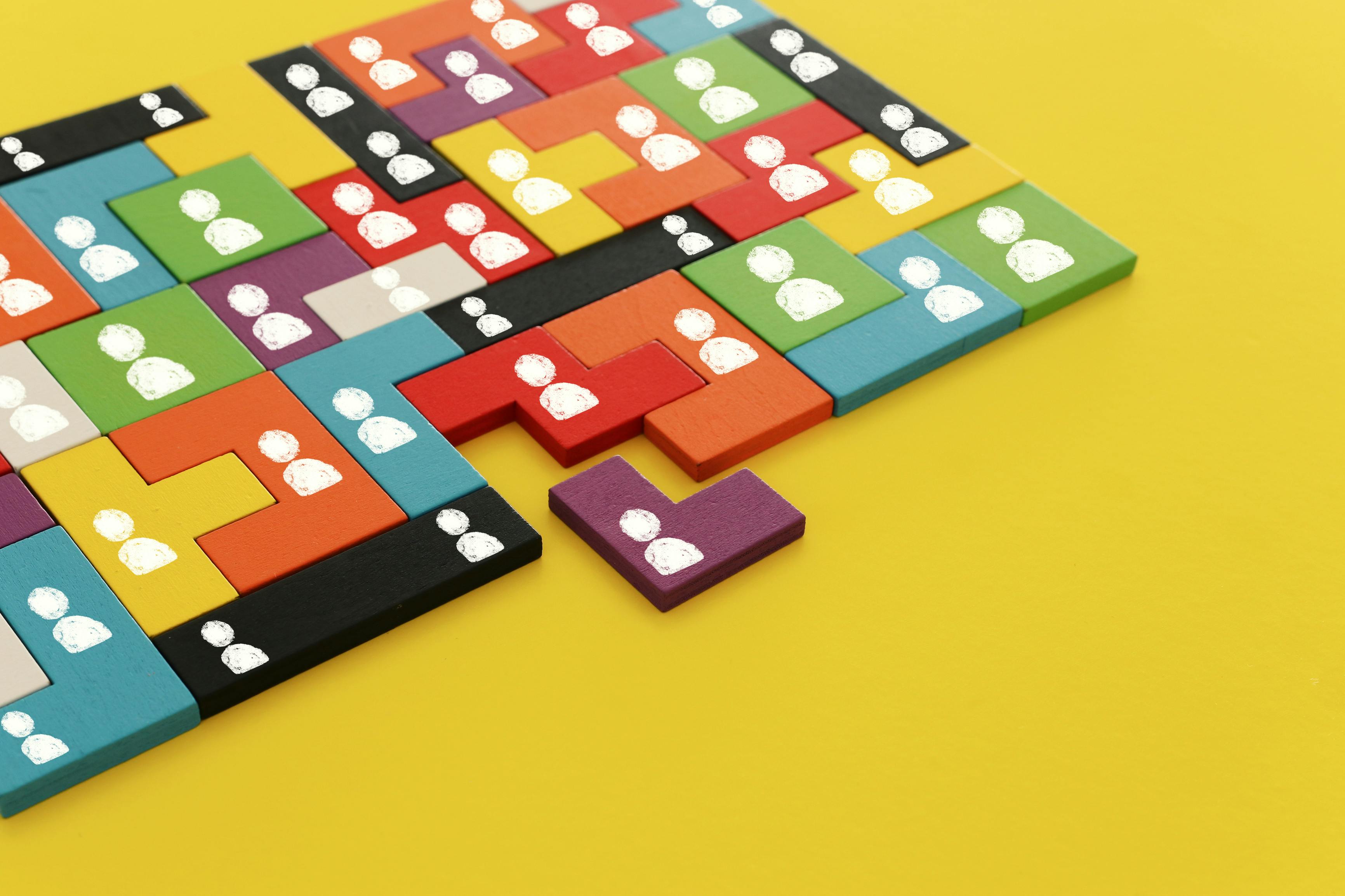Image of tangram puzzle blocks with people icons over wooden table