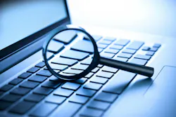 A laptop computer with a magnifying glass on the keyboard.