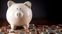 Piggy Bank on dark Hardwood Floor surrounded by scattered coins / USD money with a black background