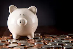 Piggy Bank on dark Hardwood Floor surrounded by scattered coins / USD money with a black background