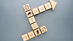 Wooden blocks with directional arrows changing path to avoid blocked routes, representing strategic pivot, business adaptation, problem solving, and navigating challenges toward success