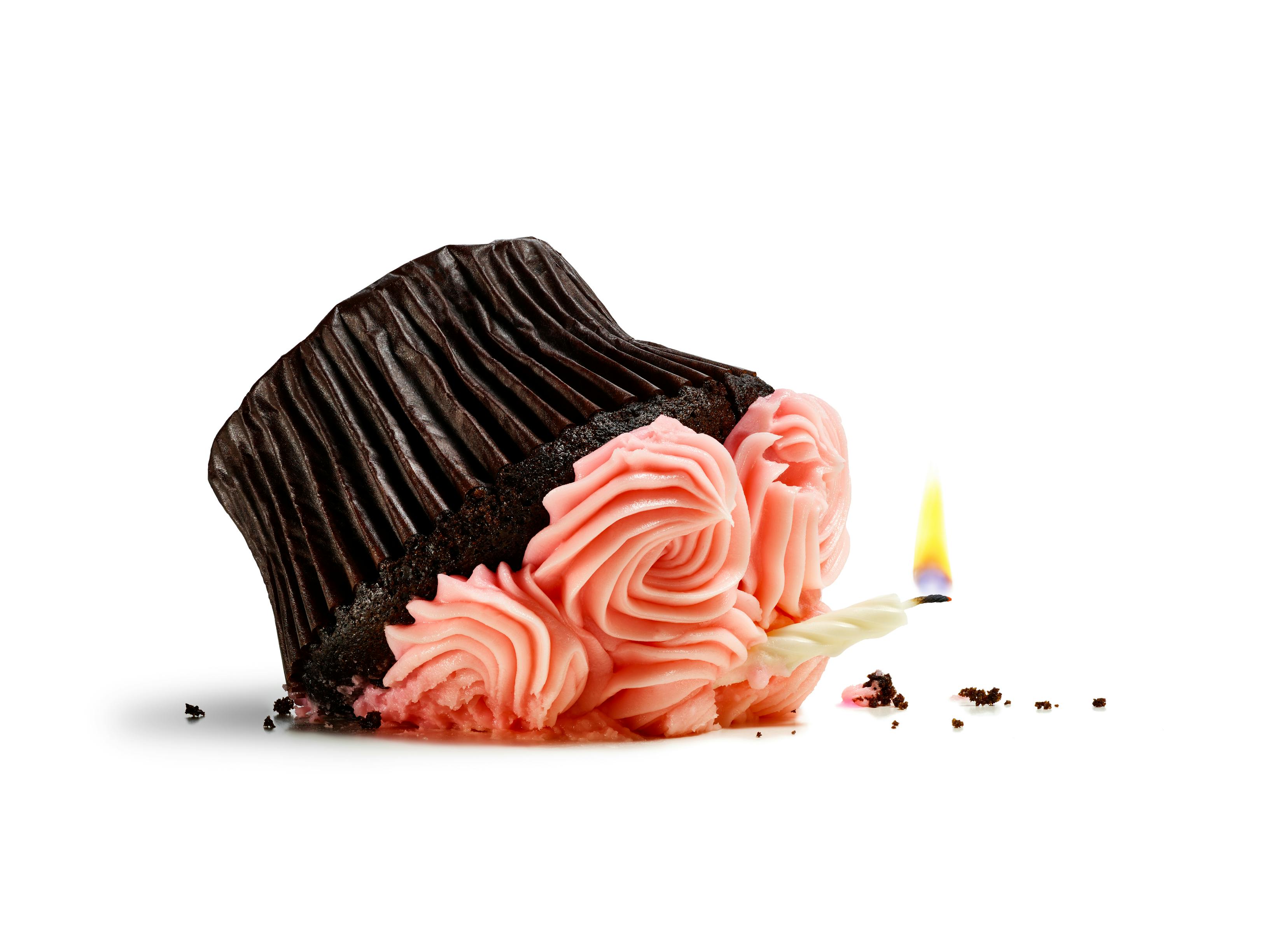 Pretty pink cupcake with candle smashed from a fall isolated on white.