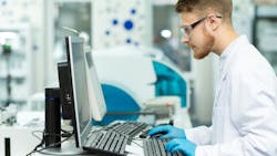 A man in a lab coat works in a computer in a healthcare lab setting. A man in a lab coat works in a computer in a healthcare lab setting.