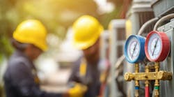 Photo of pressure gauges with blurred image of 2 workers with hardhats in the background. Photo of pressure gauges with blurred image of 2 workers with hardhats in the background.