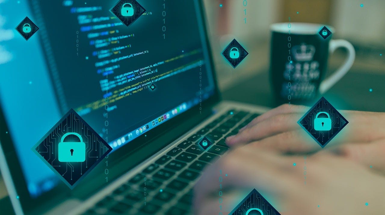 Worker at computer with code and lock symbols