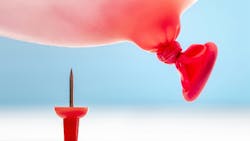 Thumbtack under a red balloon about to pop it. Thumbtack under a red balloon about to pop it.