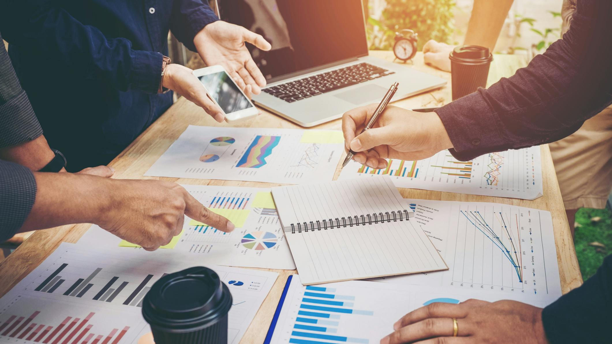 Colleagues meeting for strategy planning with data graphs and other documents.