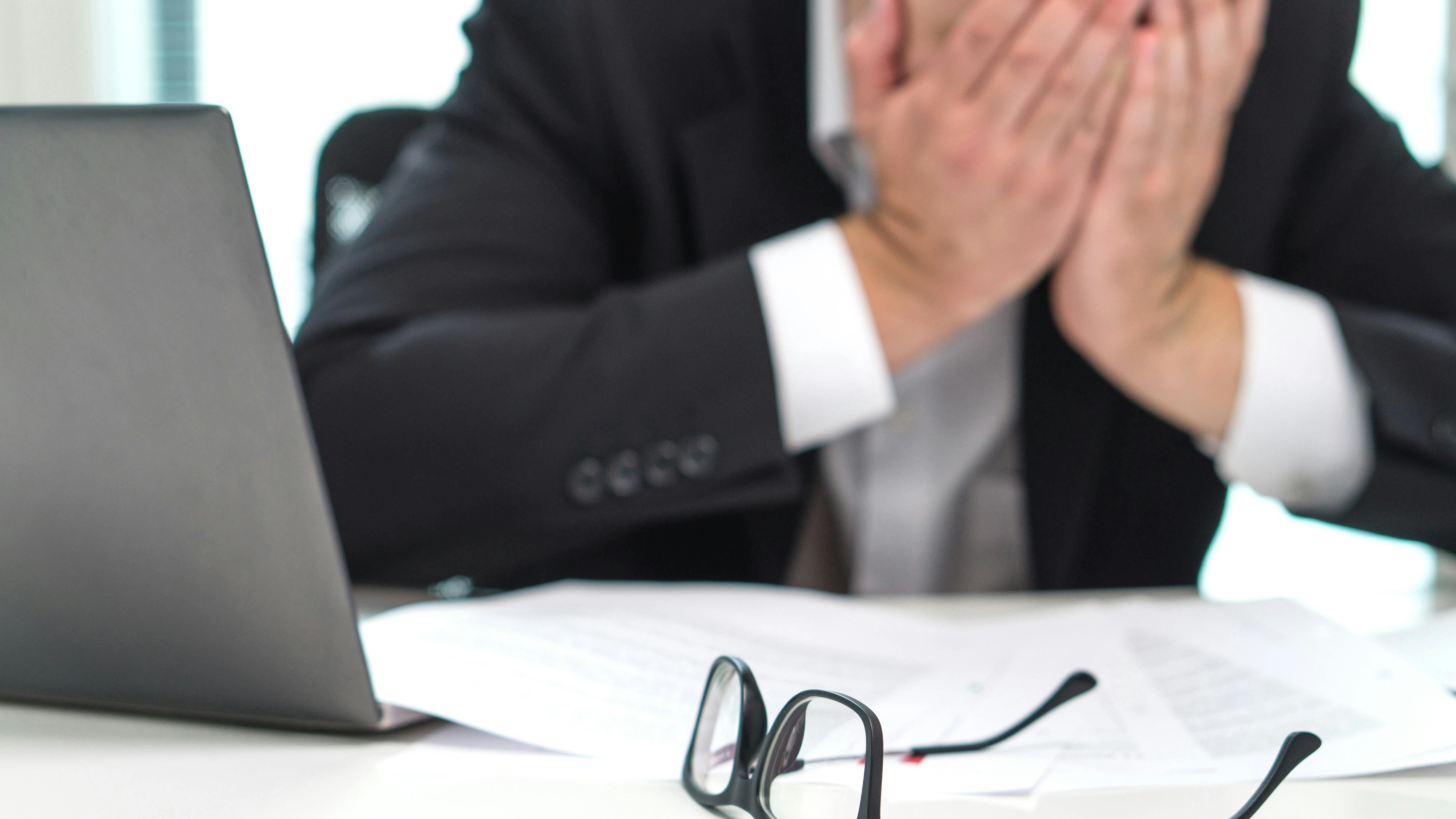 Worried businessman covering face with hands in office.