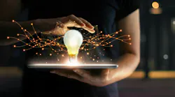 Hands holding tablet with light bulb hovering over it, on virtual interface background, representing innovation.