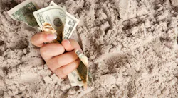 Female hand drowning in quicksand holding money.