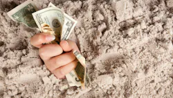 Female hand drowning in quicksand holding money.