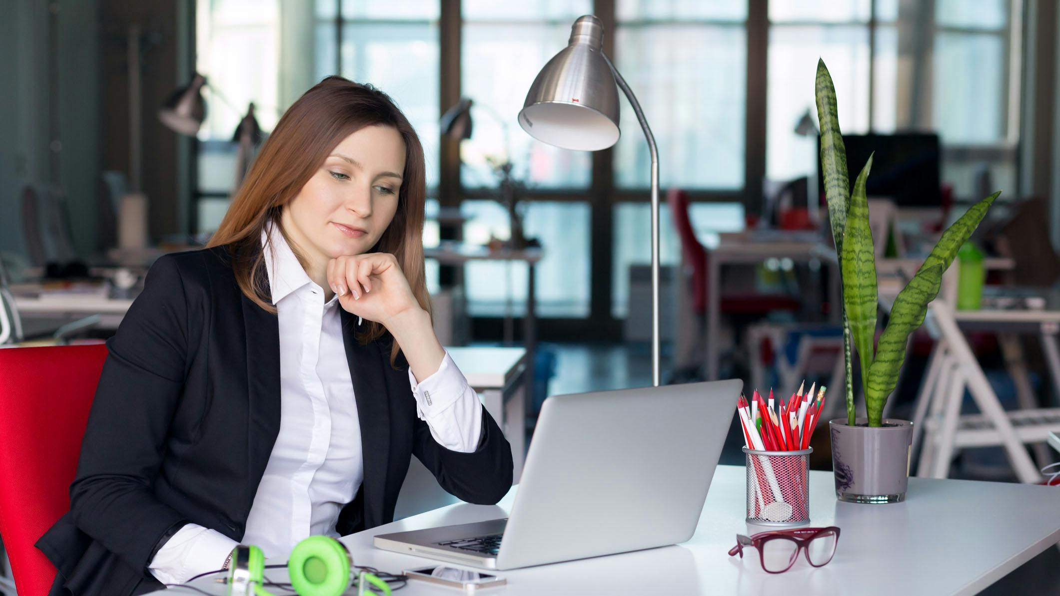 Female business leader sitting at desk thinking about decisions.