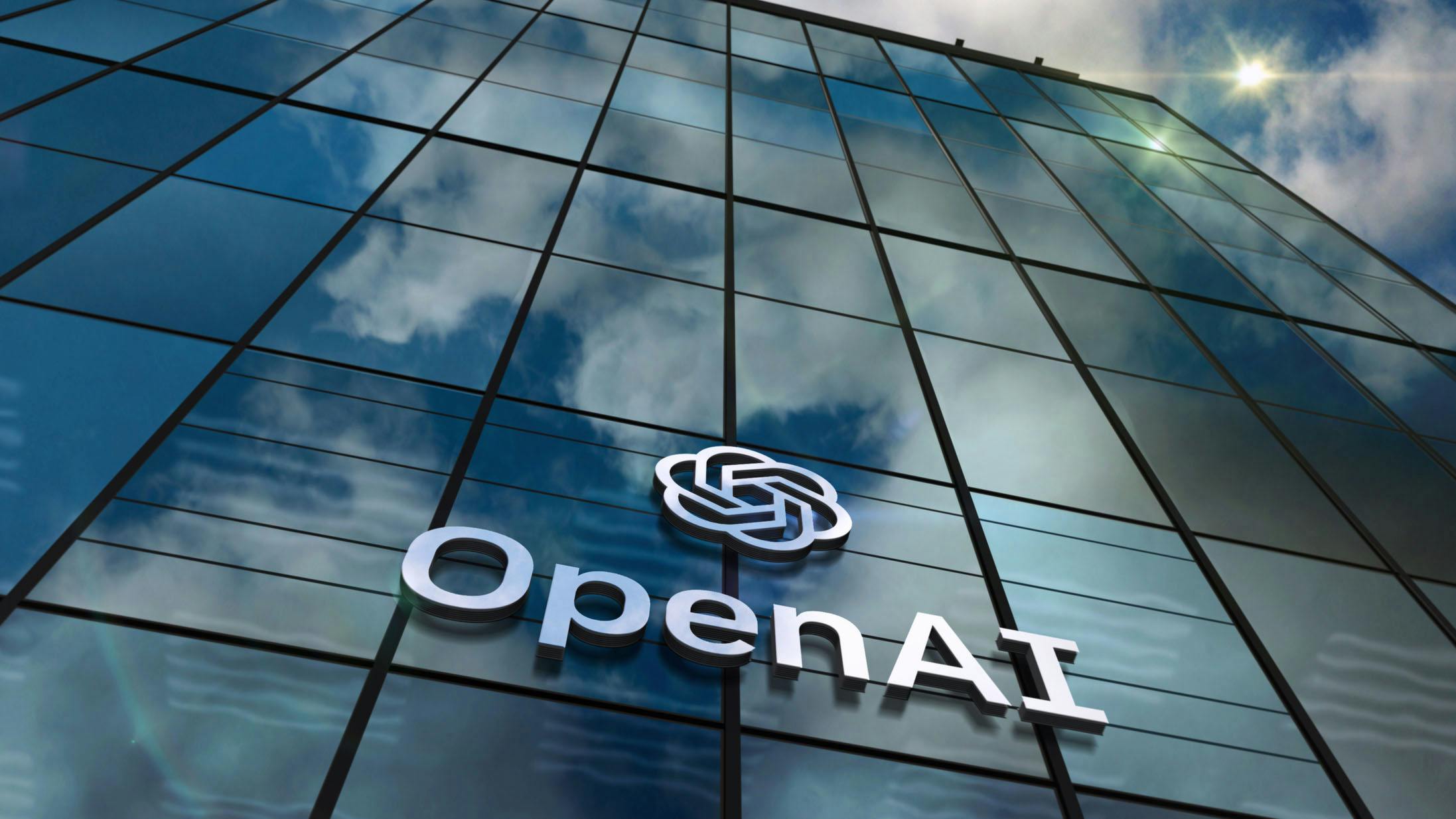 OpenAI glass building San Franciso headquarters with logo and clouds reflected on the windows.