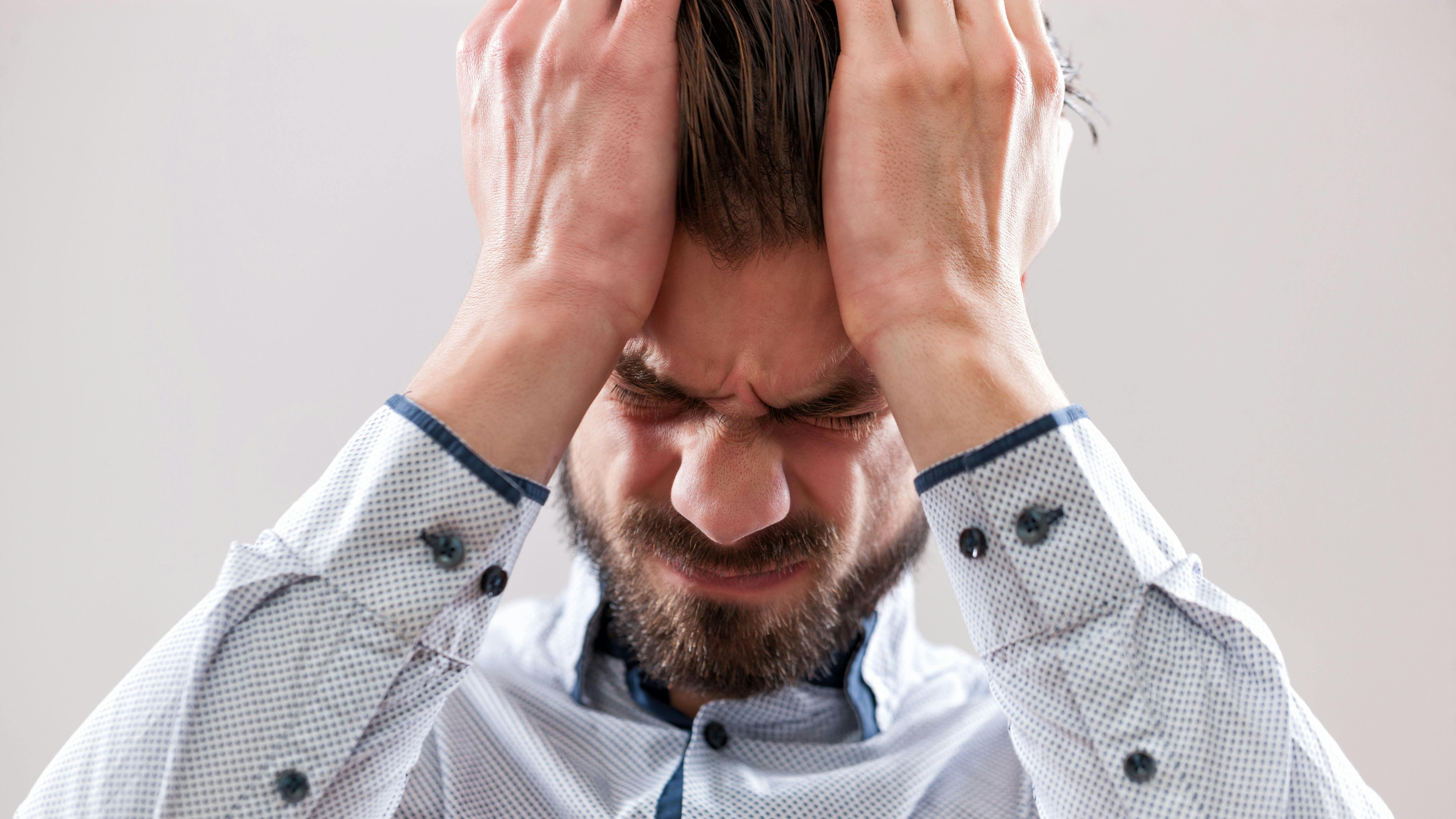 A stressed businessman with his hands on his head with a headache.