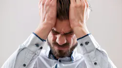 A stressed businessman with his hands on his head with a headache.