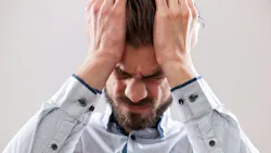 A stressed businessman with his hands on his head with a headache.